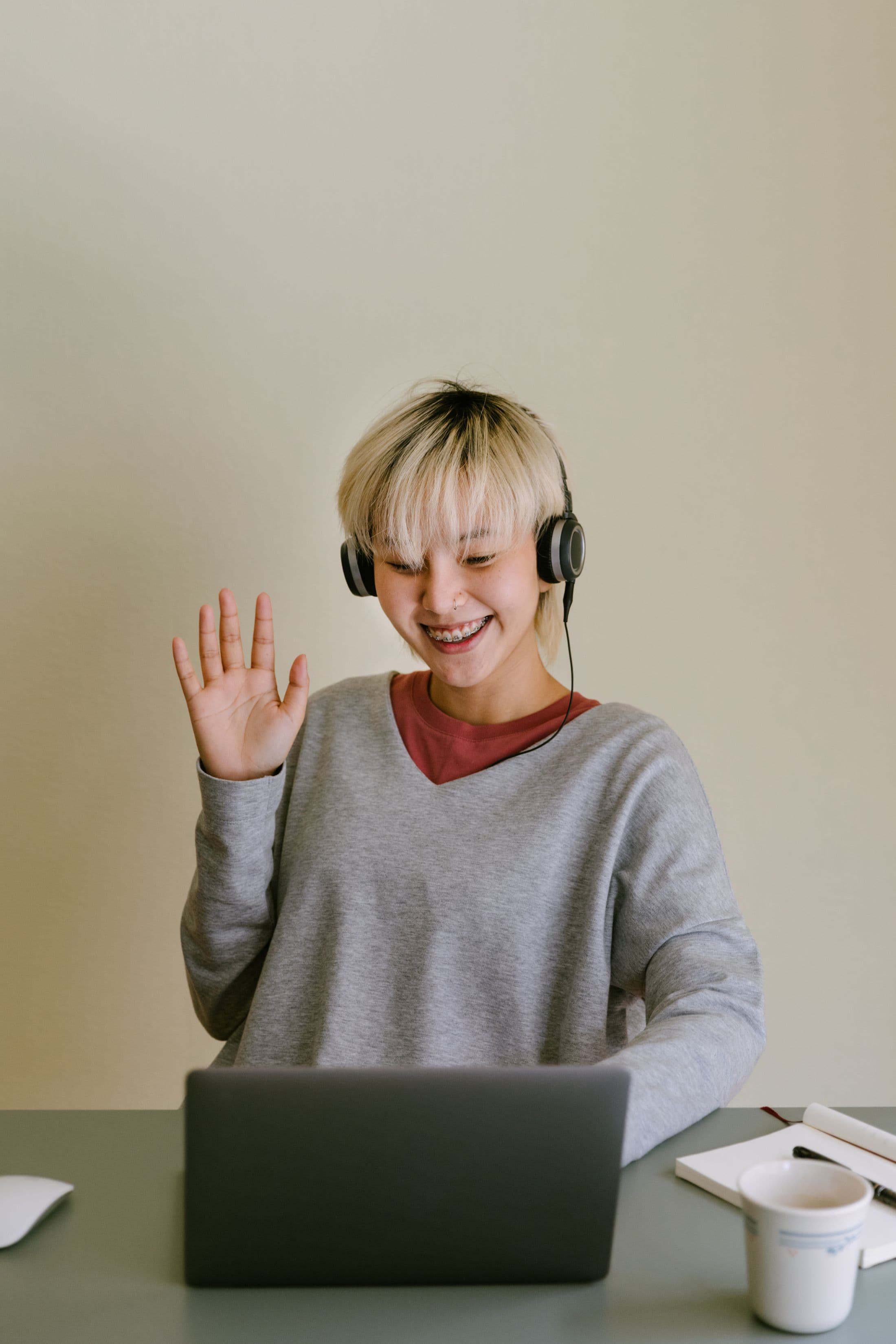 Student greeting an online tutor from a laptop